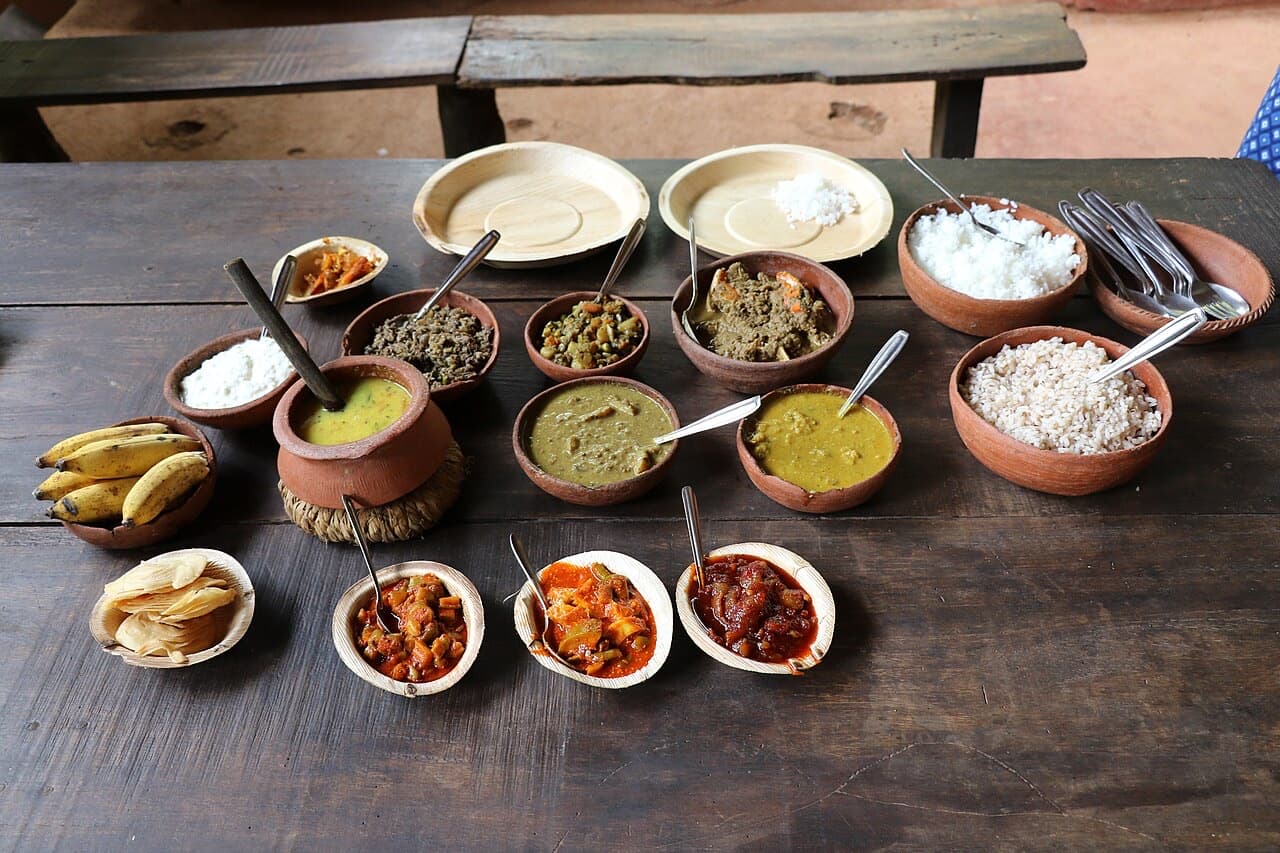 Traditional Goan meal laid out in clay bowls on a wooden table in Goa