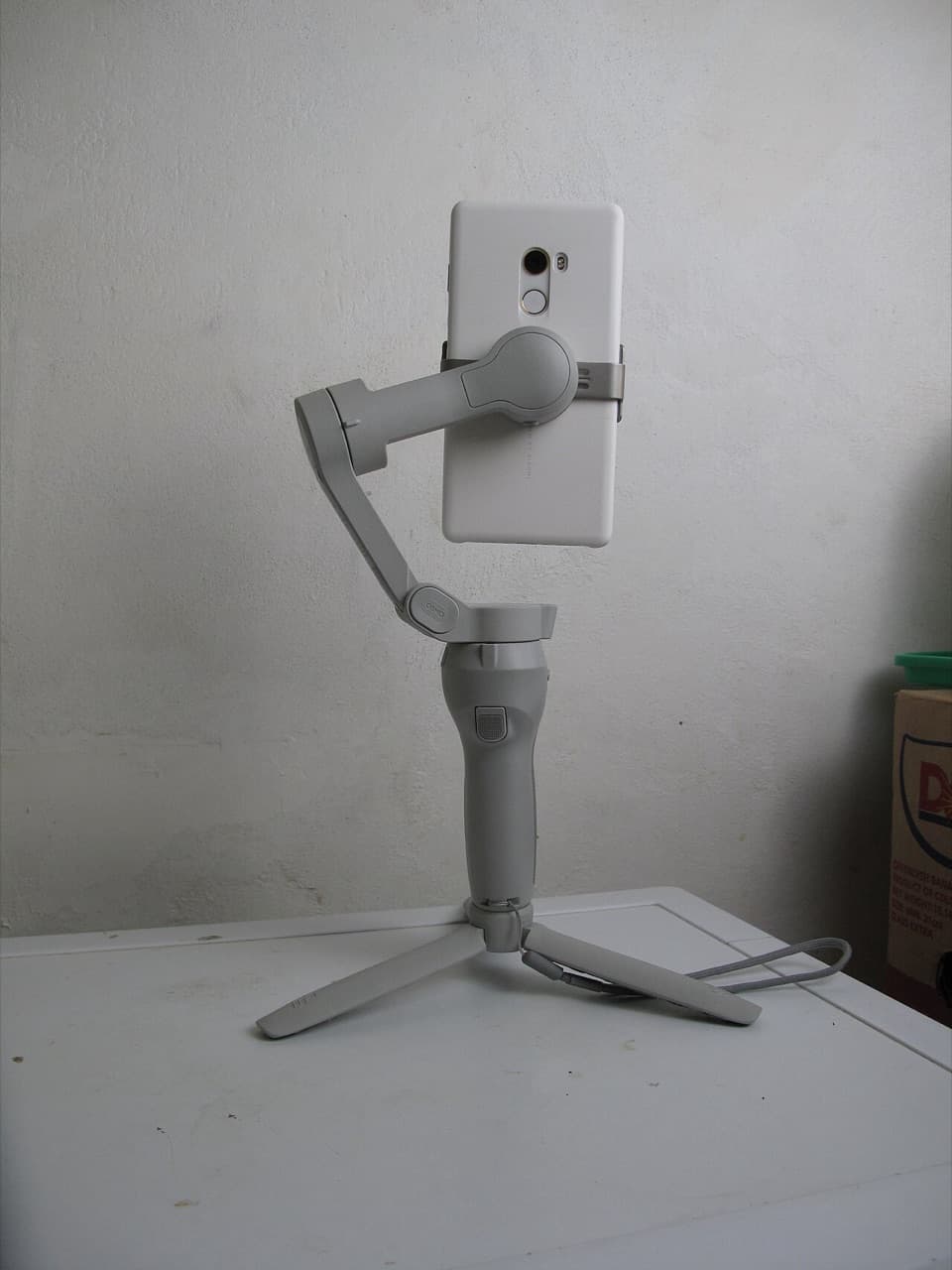 DJI smartphone gimbal on its tripod, rear view showing the magnetic phone clamp and folding arm