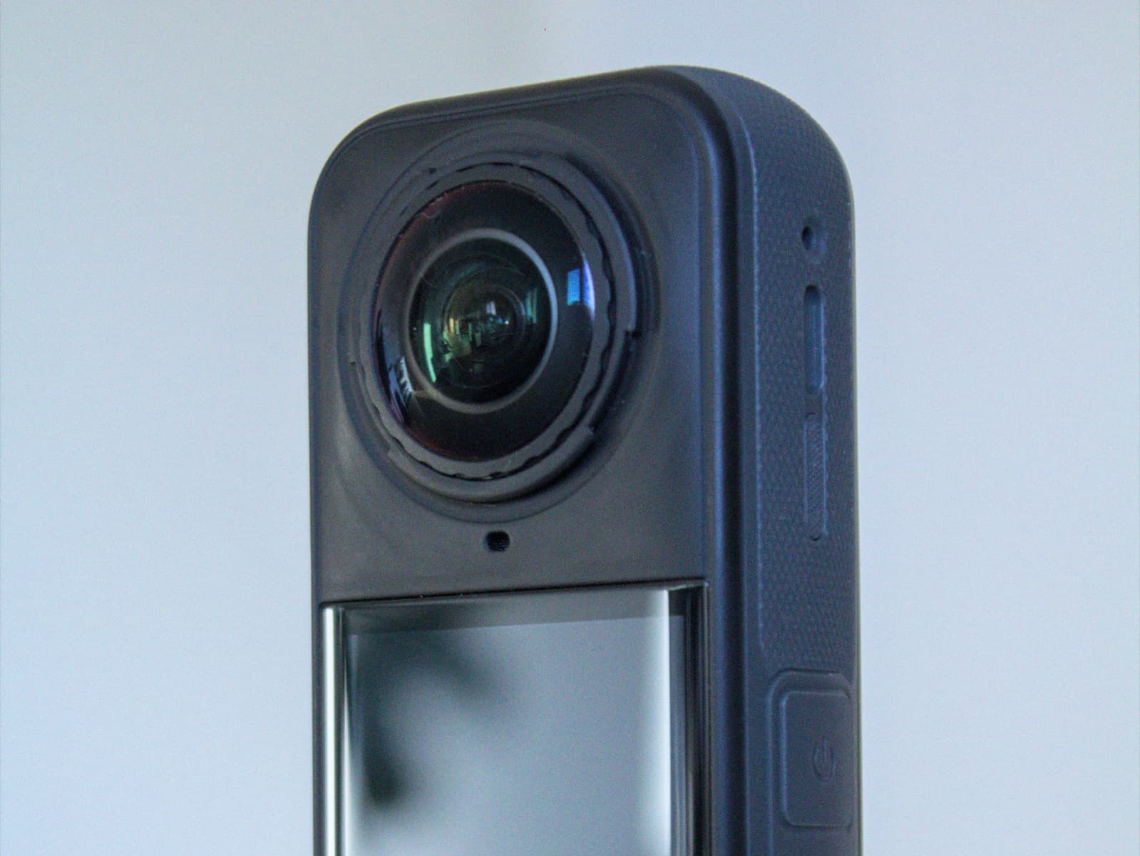 Close-up of the top of a dark grey Insta360 camera showing its round fisheye lens above the screen