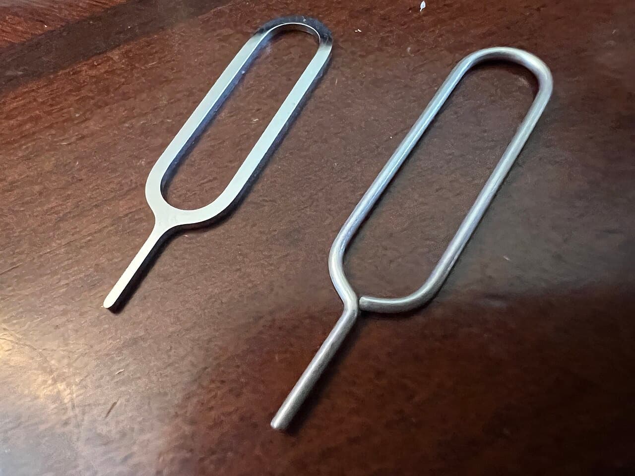 Two SIM ejector pins on a wooden table