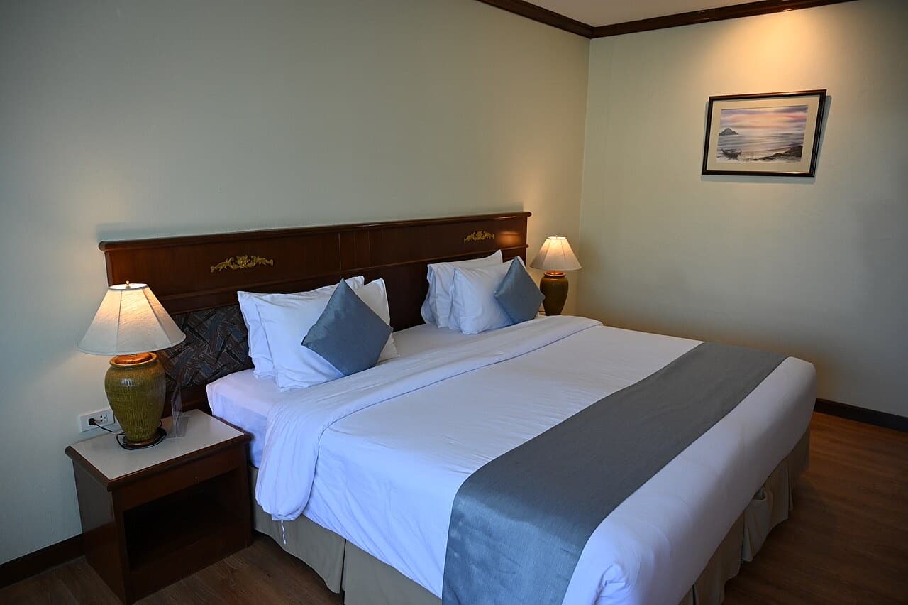 Freshly made king bed with crisp white linen and bedside lamps