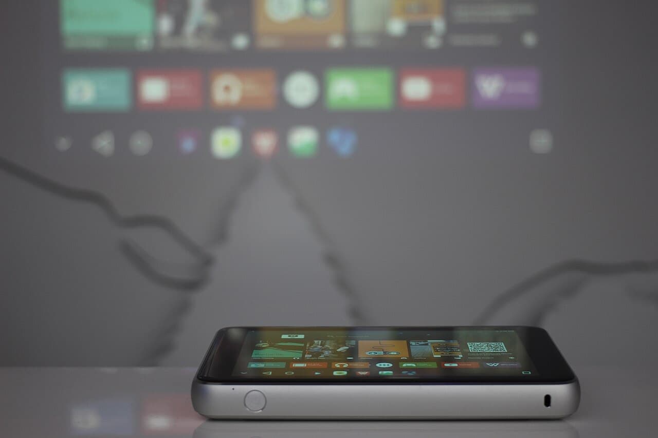 Portable projector on a table projecting its app home screen onto the wall behind it