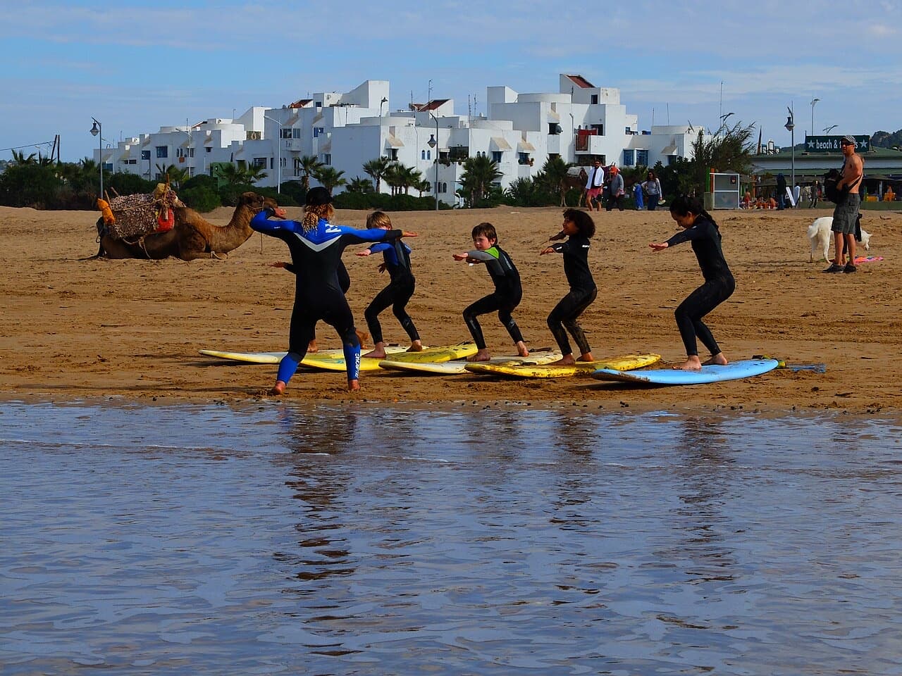 Beginner surf lesson practising the pop-up on foam boards laid on the sand
