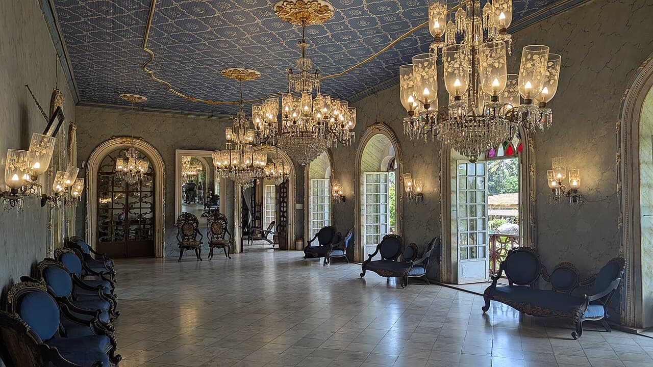 The ballroom at Menezes Braganza House with crystal chandeliers, a patterned ceiling and carved chairs