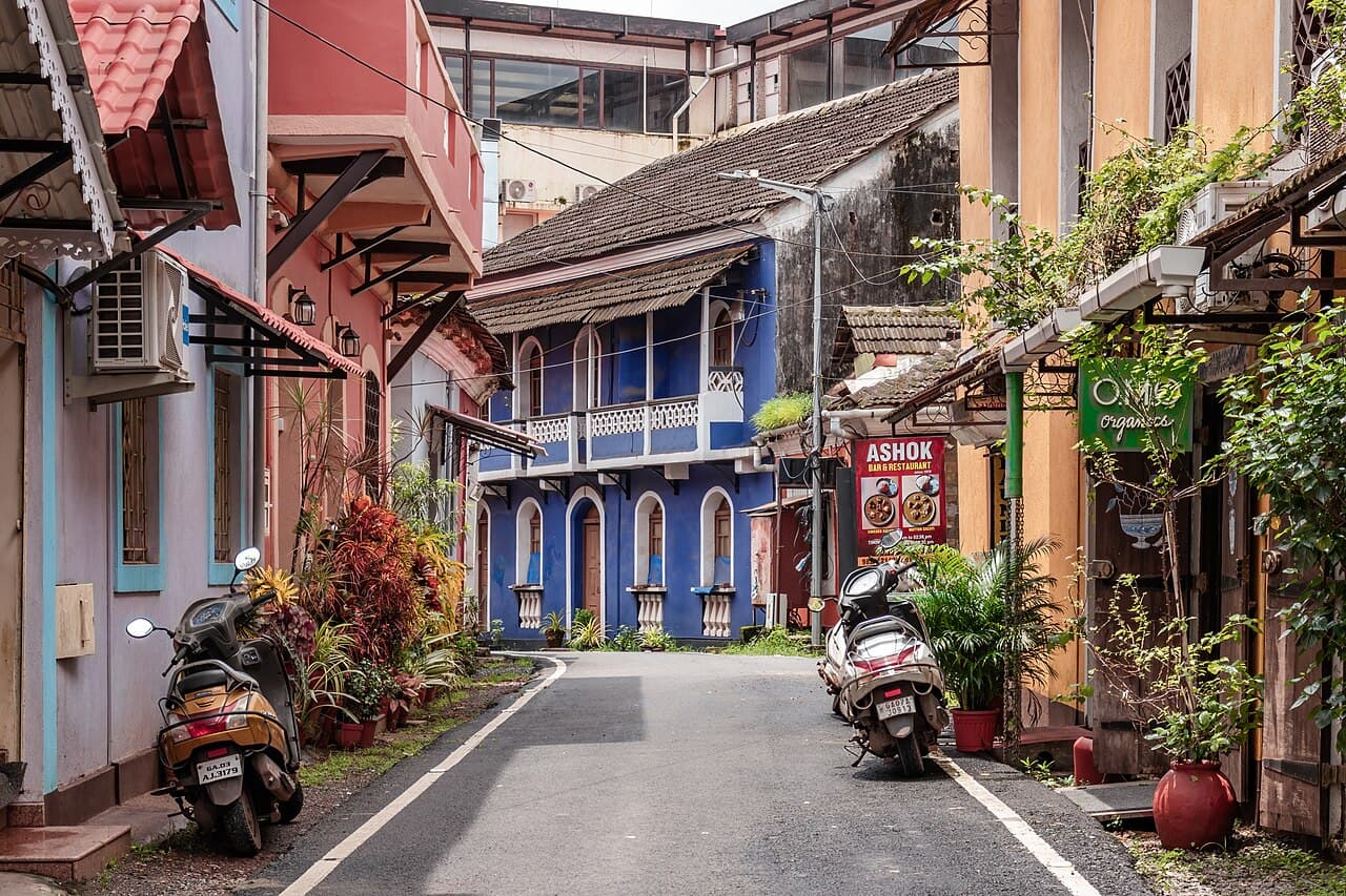Scooters parked on a narrow street in Fontainhas, Panaji, lined with colourful old houses and a blue balcony home